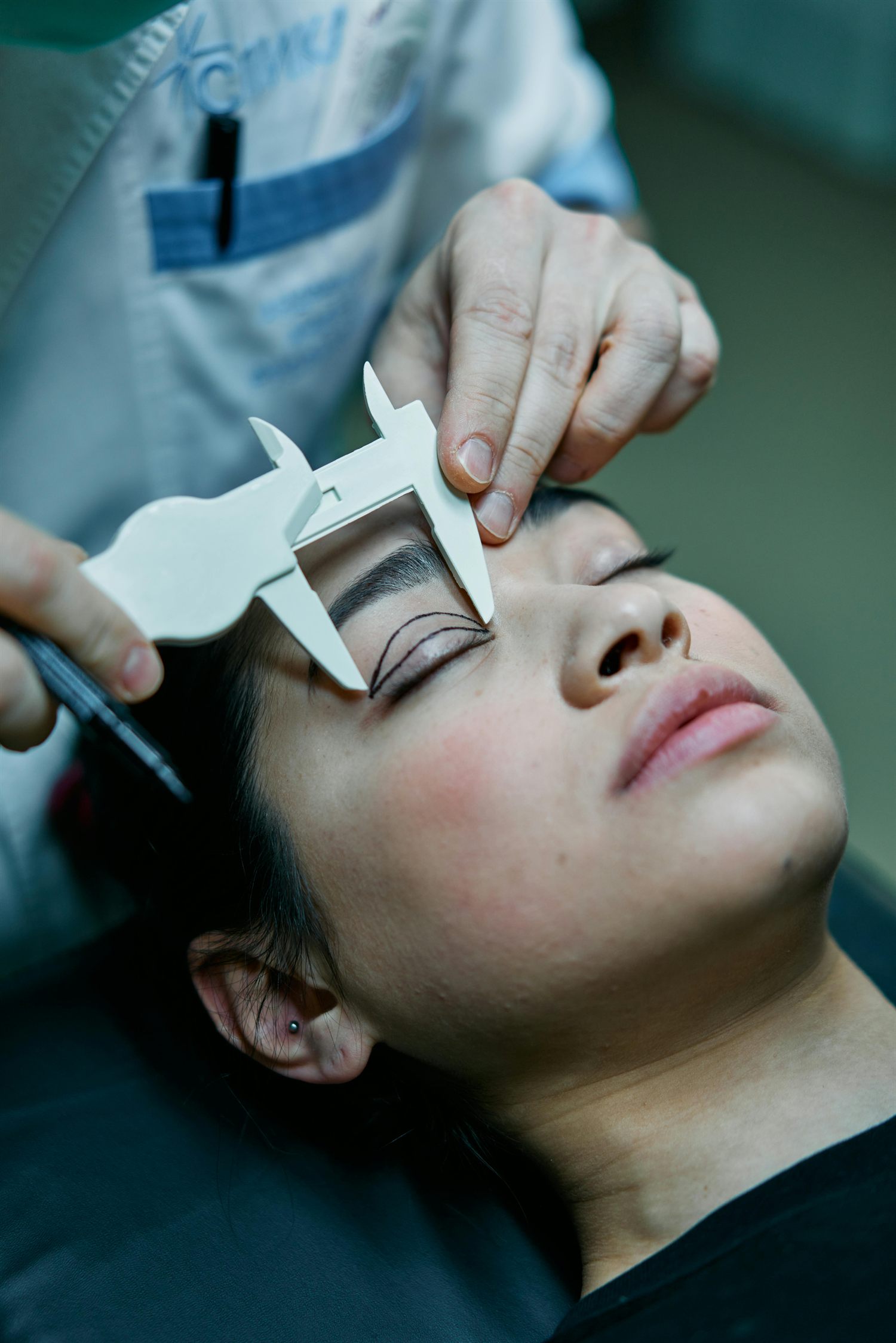 Surgeon marking brow proportions during a facial procedure consultation